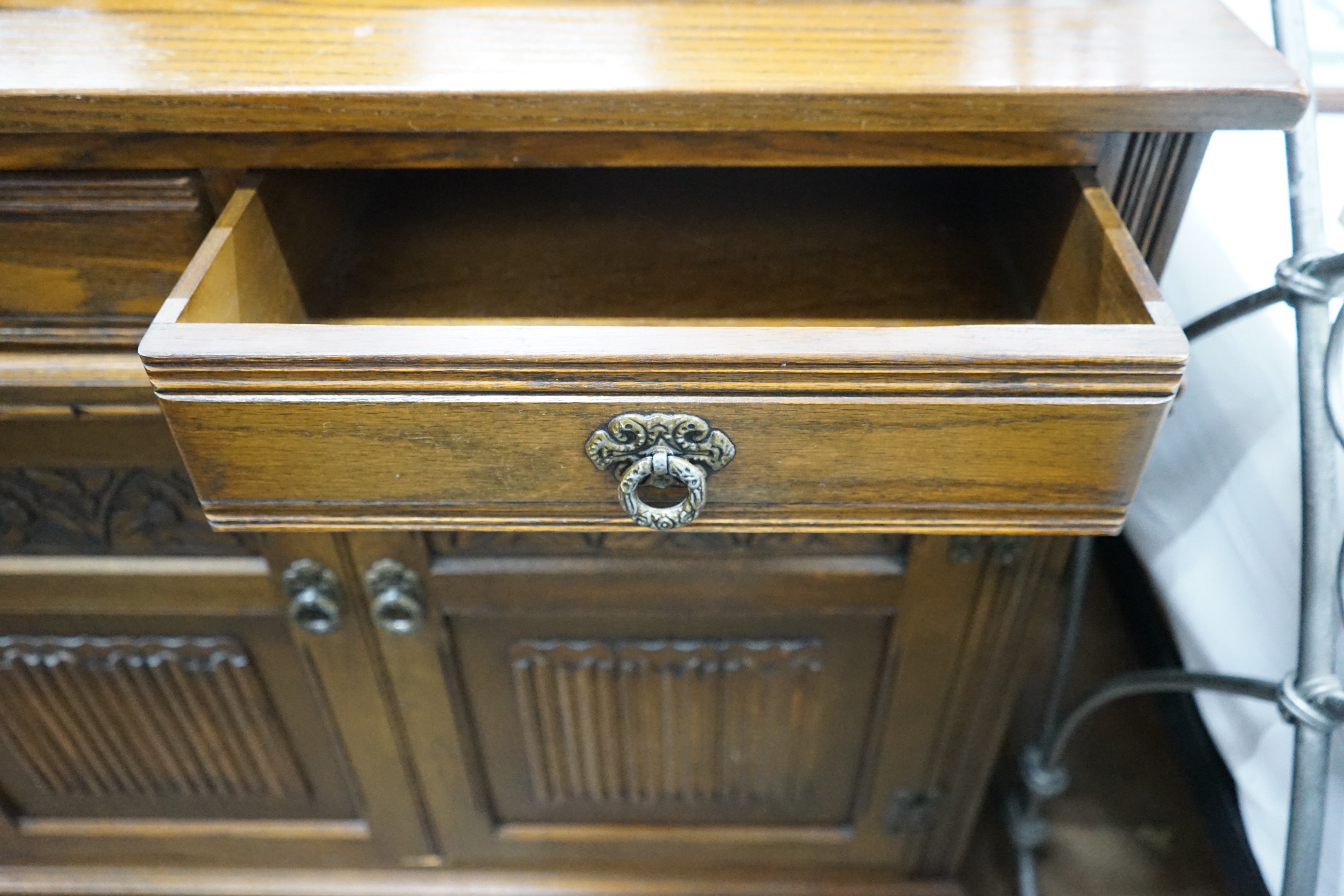 A reproduction 18th century style carved and linen fold moulded oak sideboard width 187cms, depth 44cms, height 87cms.
